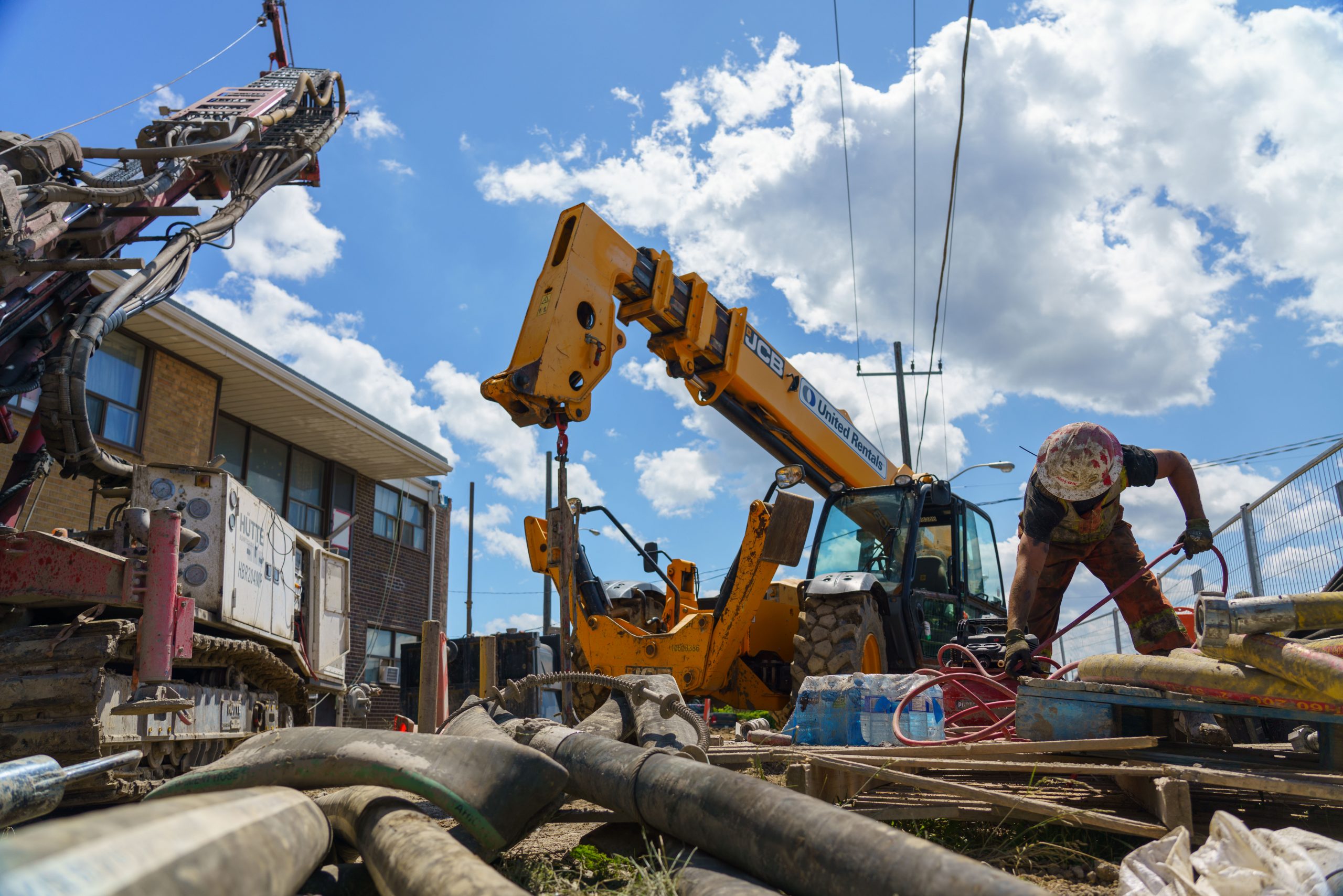 A construction site with a worker in the foreground and machinery in the background.