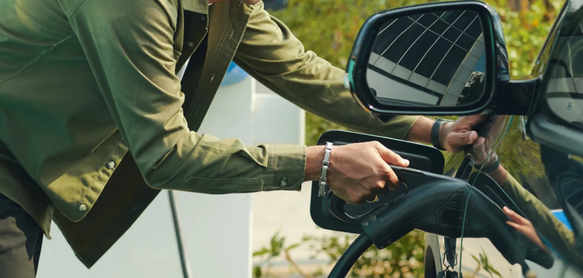 A person plugs in their EV for a charge.